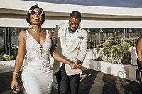 Carina and Marvin smile, holding hands as they walk outside at their destination wedding.