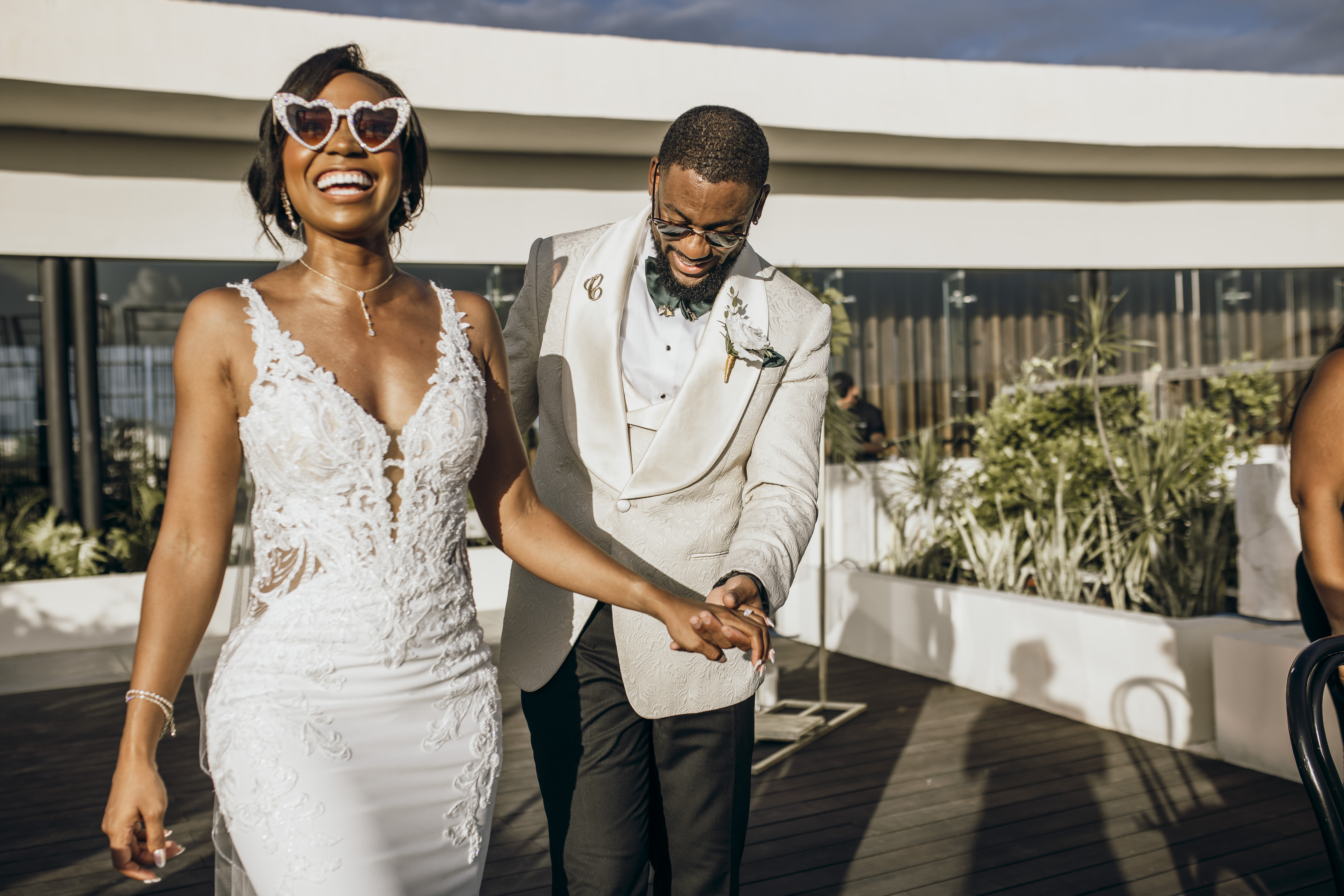 Carina and Marvin smile, holding hands as they walk outside at their destination wedding.