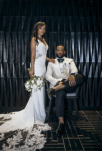 Carina and Marvin pose together at their destination wedding against a dark geometric wall.
