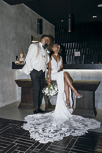 Carina and Marvin at their destination wedding—bride seated with bouquet and train, both dressed formally.