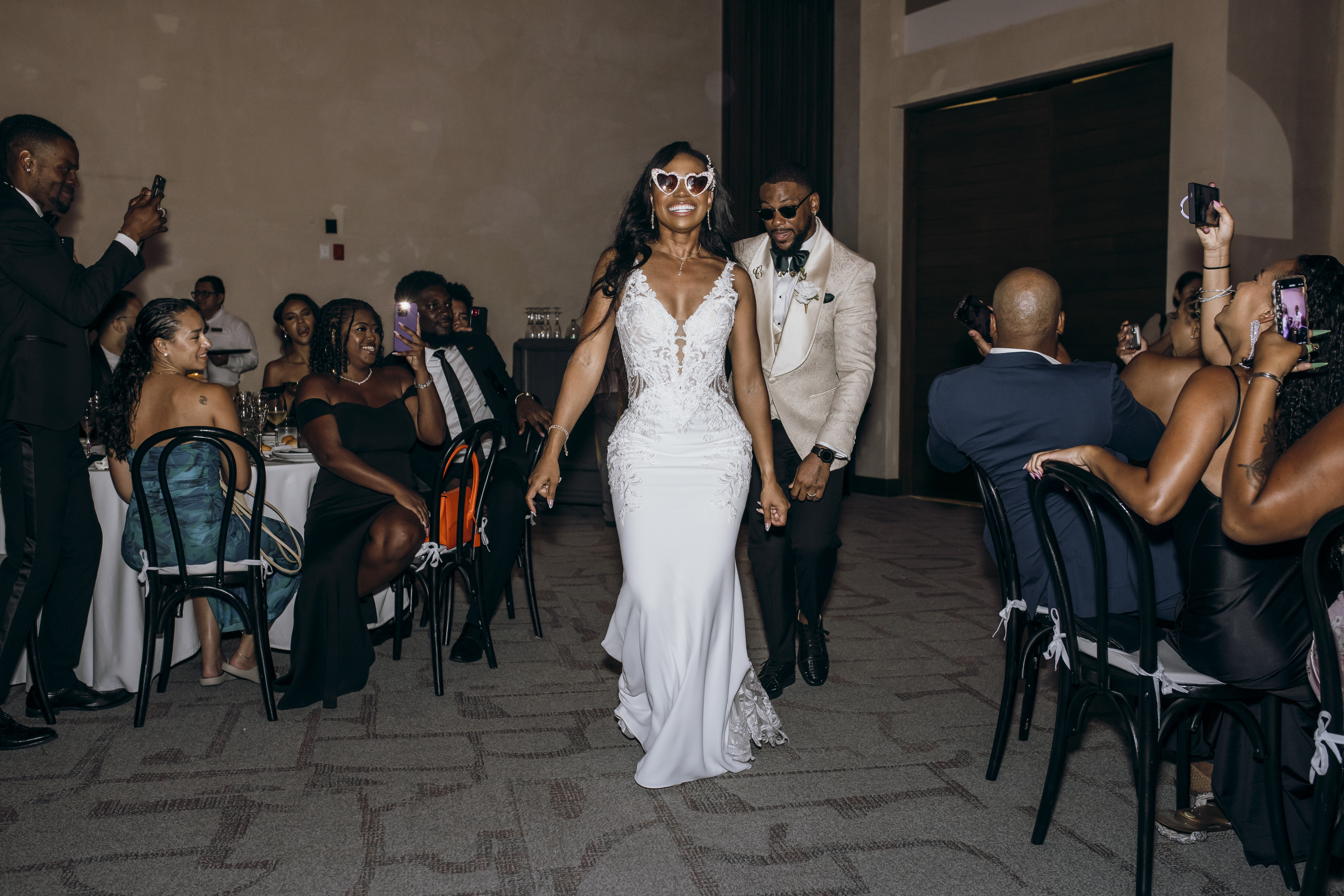 Carina and Marvin make their wedding entrance into the reception hall as guests watch and snap photos.