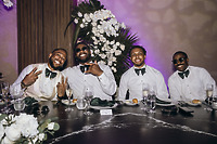 Four men in white shirts and bow ties sit at a table during a destination wedding with Carina and Marvin.