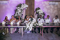 Carina and Marvin's destination wedding party shares toasts at a floral-adorned reception table.
