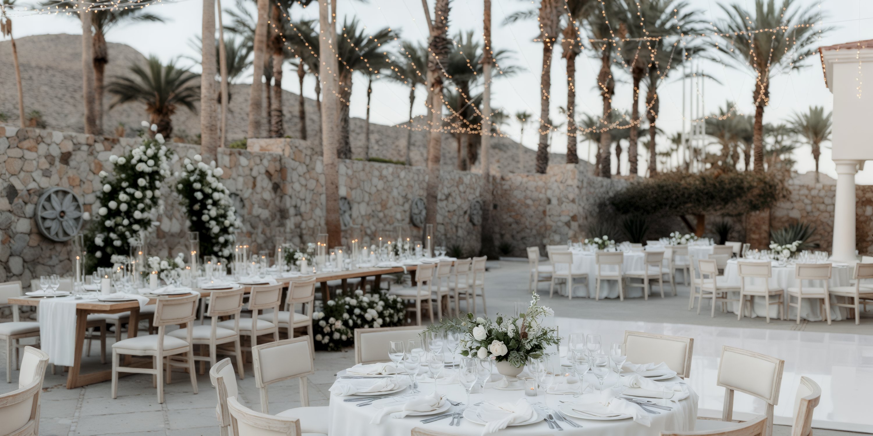 A sophisticated destination wedding arrangement featuring elegantly adorned tables and chairs, enhanced by the gentle glow of string lights and exquisite floral decorations.