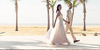 Bride and groom hold hands by palm trees during their destination wedding at Nobu Hotel Los Cabos.