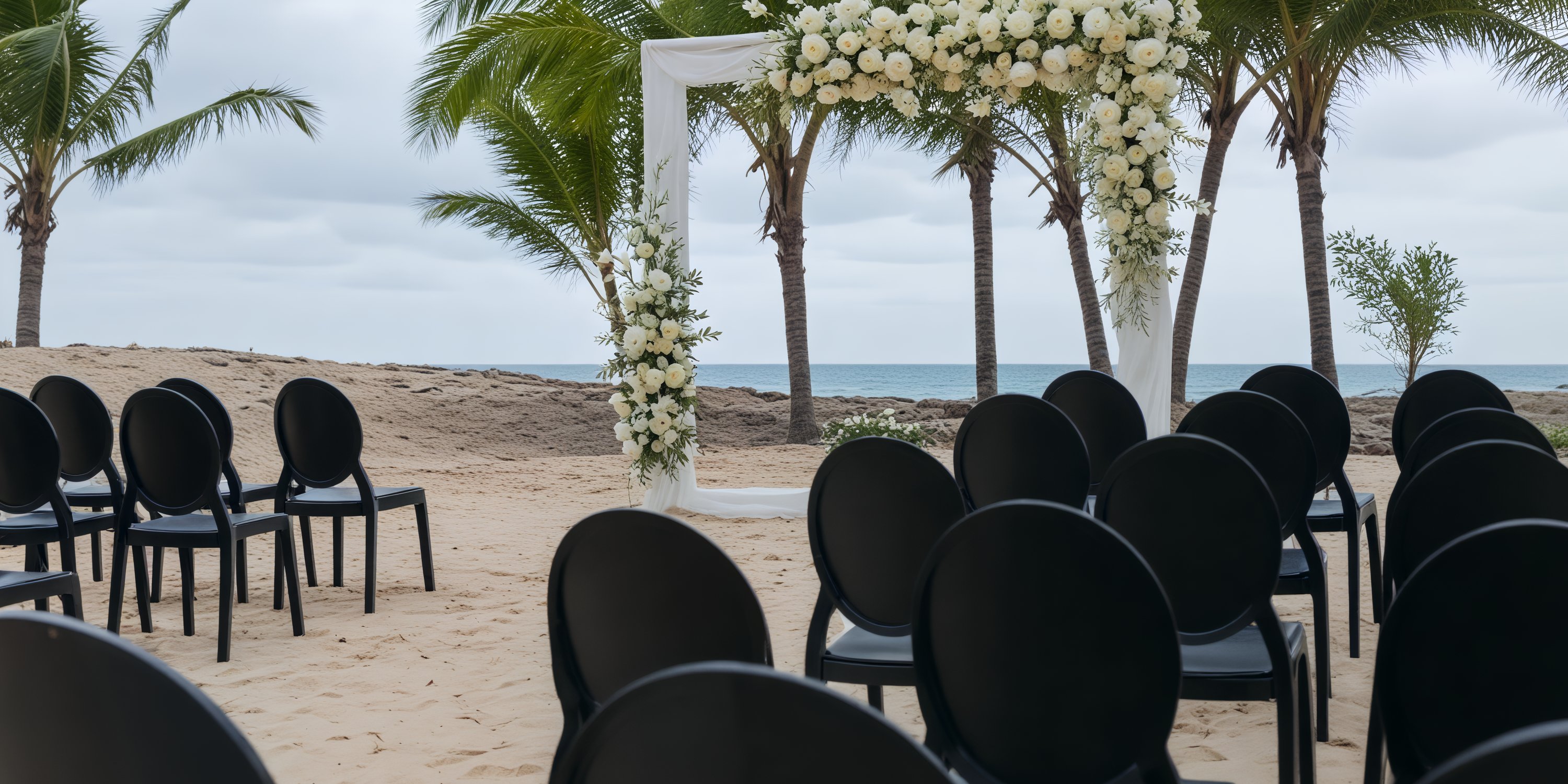 Black chairs arranged for a destination wedding face a floral arch on the sand at Dreams Playa Esmeralda.