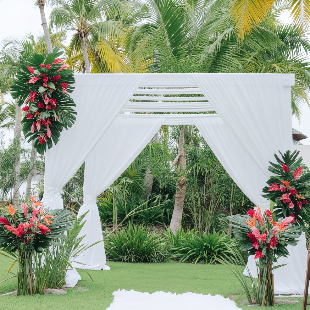 A white wedding arch adorned with tropical flowers stands elegantly amidst a backdrop of palm trees, creating a perfect setting for a destination wedding.