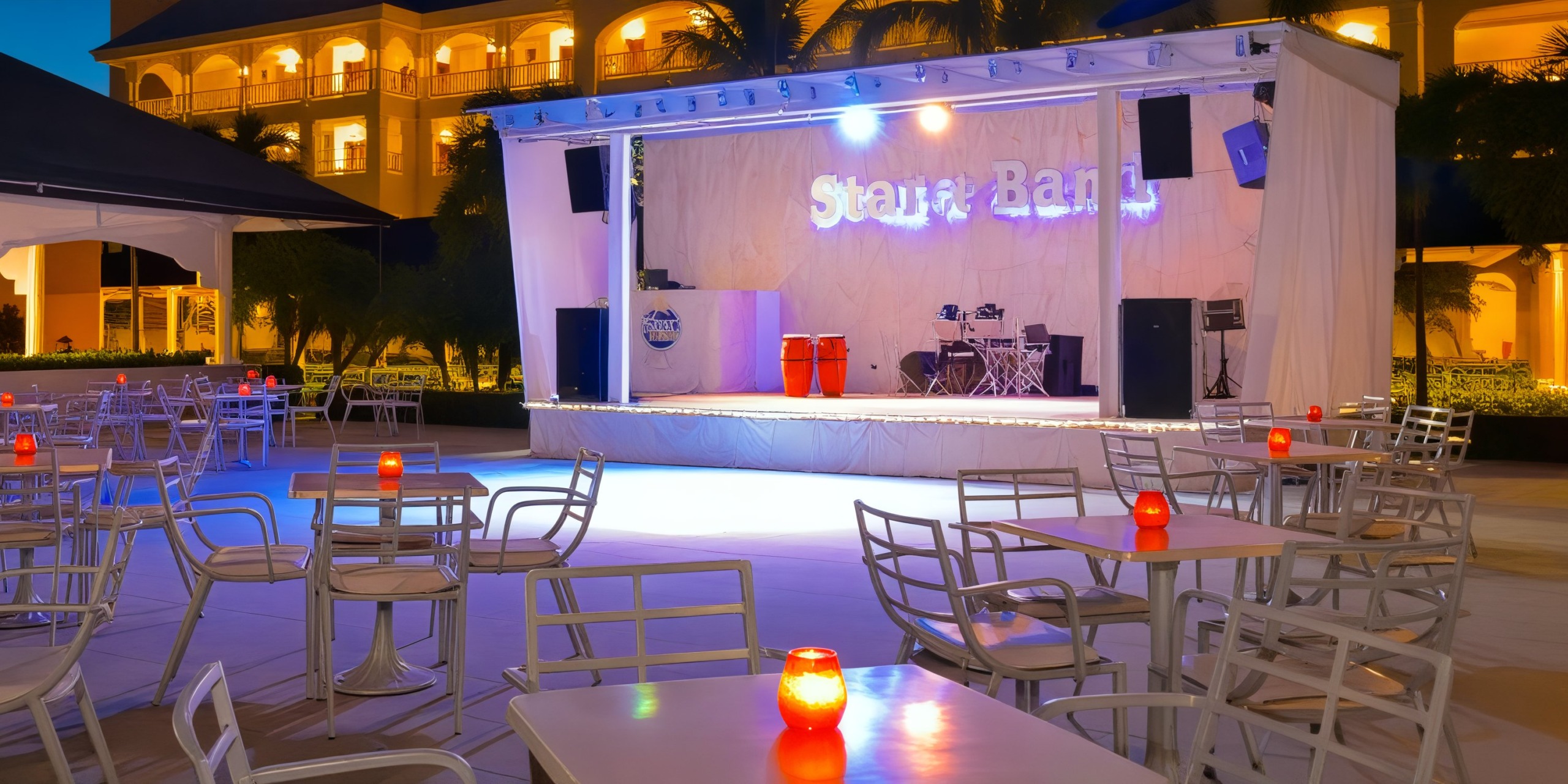 An outdoor stage adorned with tables and chairs, surrounded by glowing candles under the night sky, perfect for a romantic destination wedding.