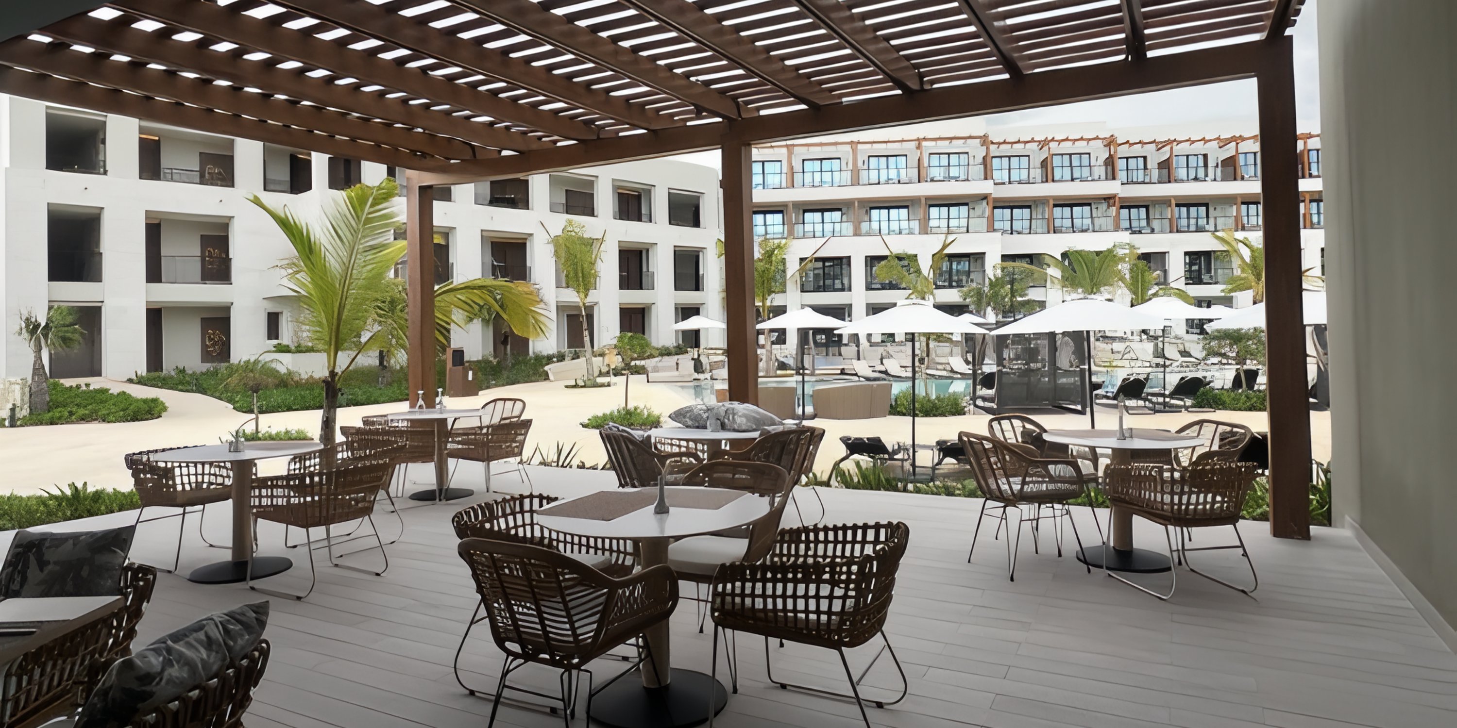 Secrets Playa Esmeralda patio with wicker chairs, ideal for a destination wedding, overlooks the pool.