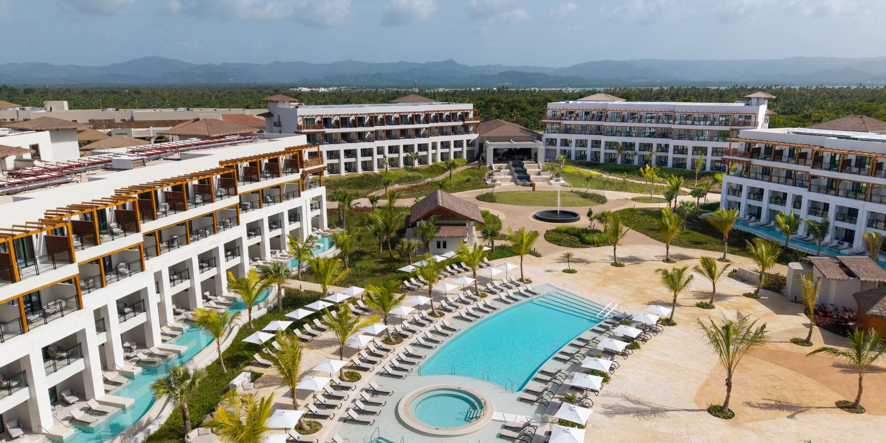 Aerial view of Secrets Playa Esmeralda, a destination wedding spot with pools, lounge chairs, and palms.