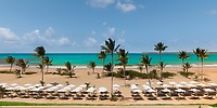 Palm trees, sandy beach, and loungers with umbrellas at Secrets Playa Esmeralda, ideal for a wedding.