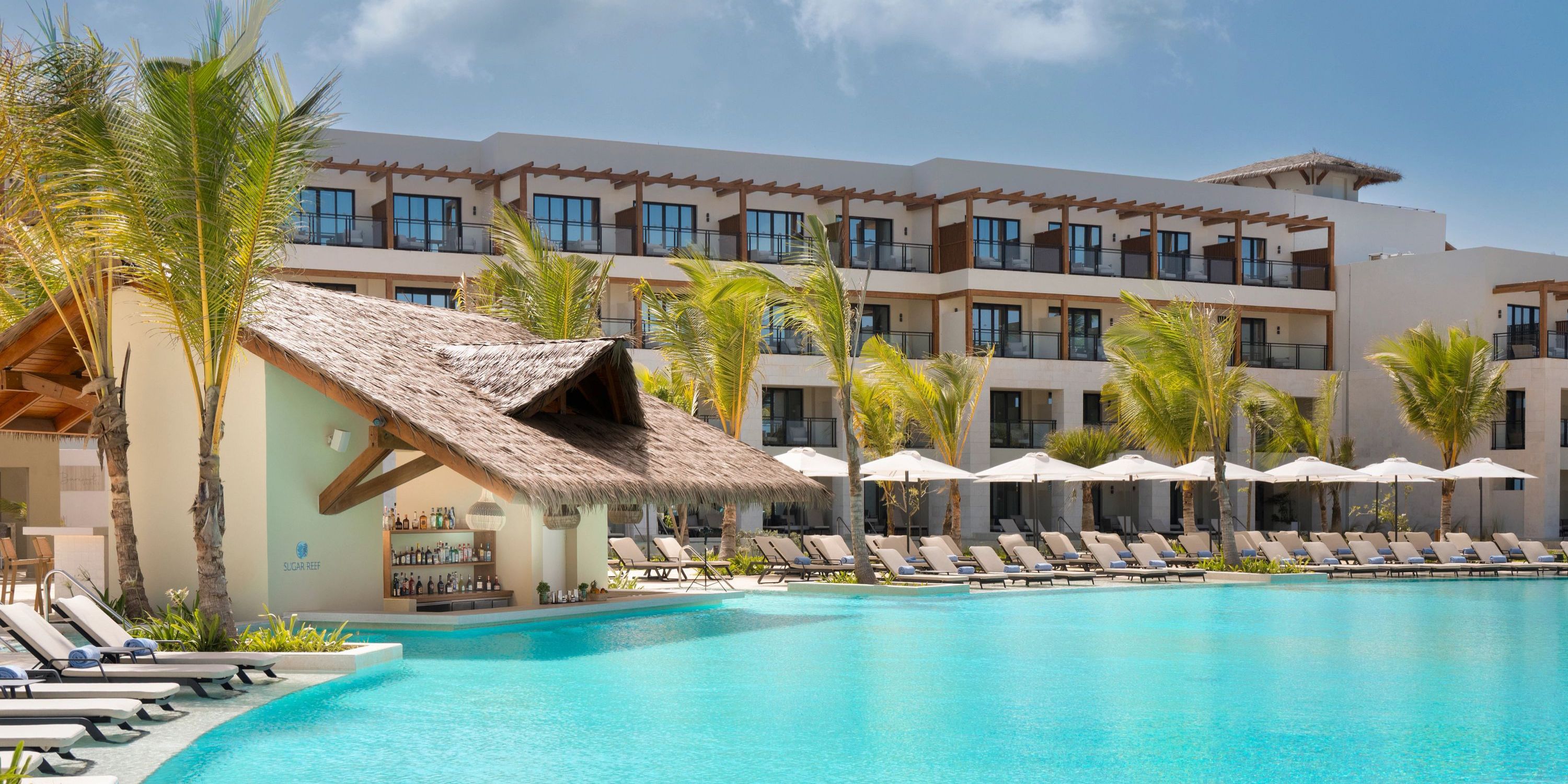 Secrets Playa Esmeralda: resort pool with lounge chairs, umbrellas, palm trees—ideal for a destination wedding.
