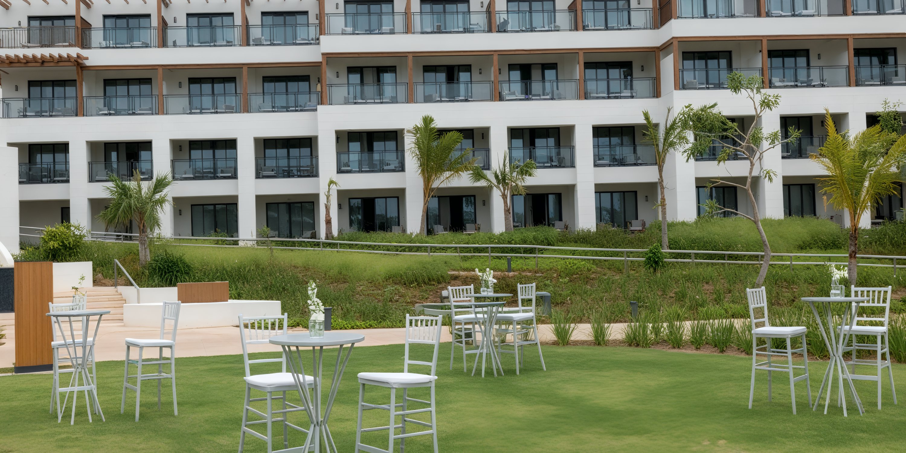 Destination wedding setup with white tables and chairs on grass at Secrets Playa Esmeralda hotel.