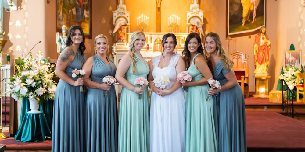 Bride and bridesmaids in matching dresses hold bouquets at a decorated church during a wedding ceremony.