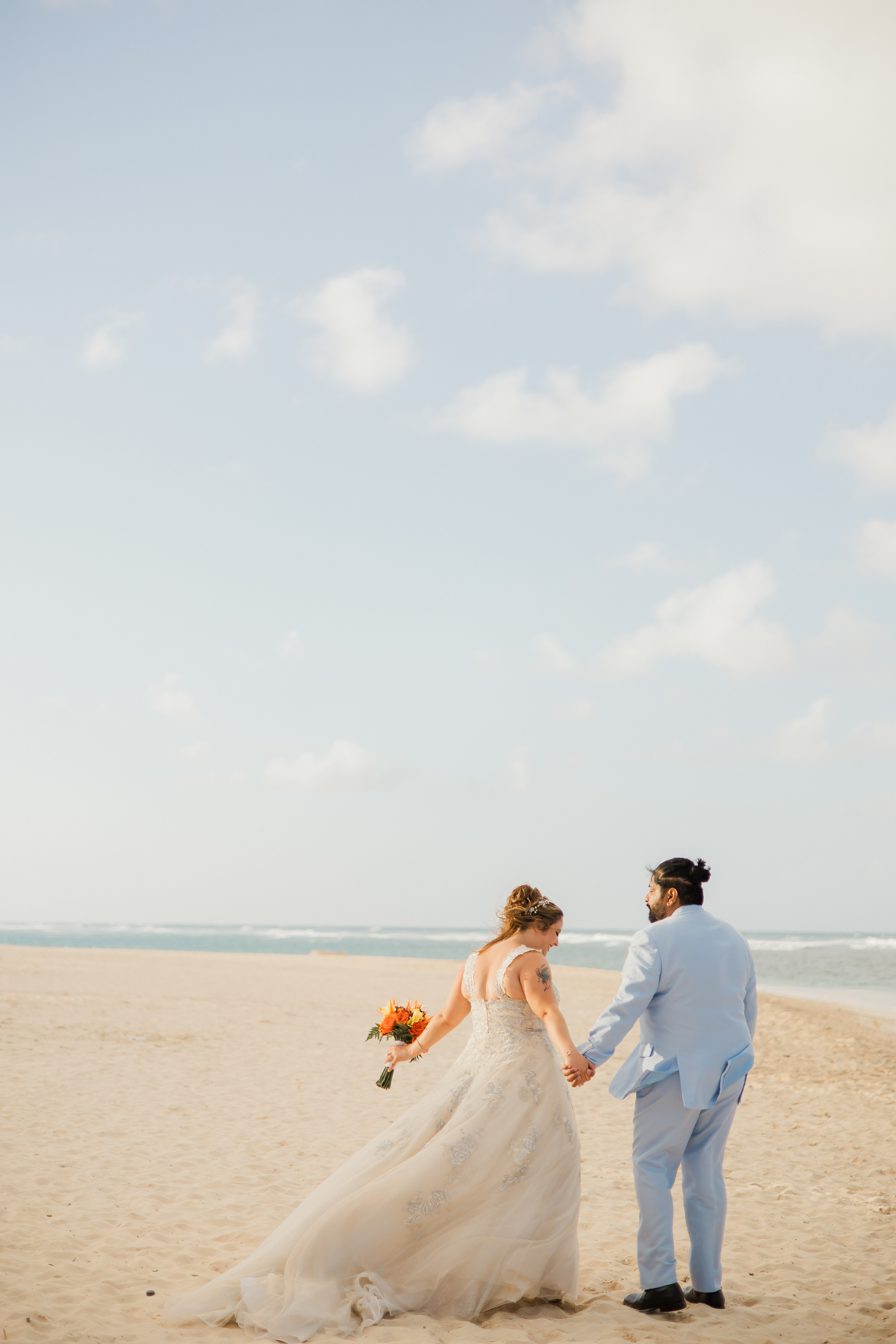 Albrianna and Nicholas, hand in hand, strolled along the sandy beach under a partly cloudy sky, embracing the magic of their destination wedding.