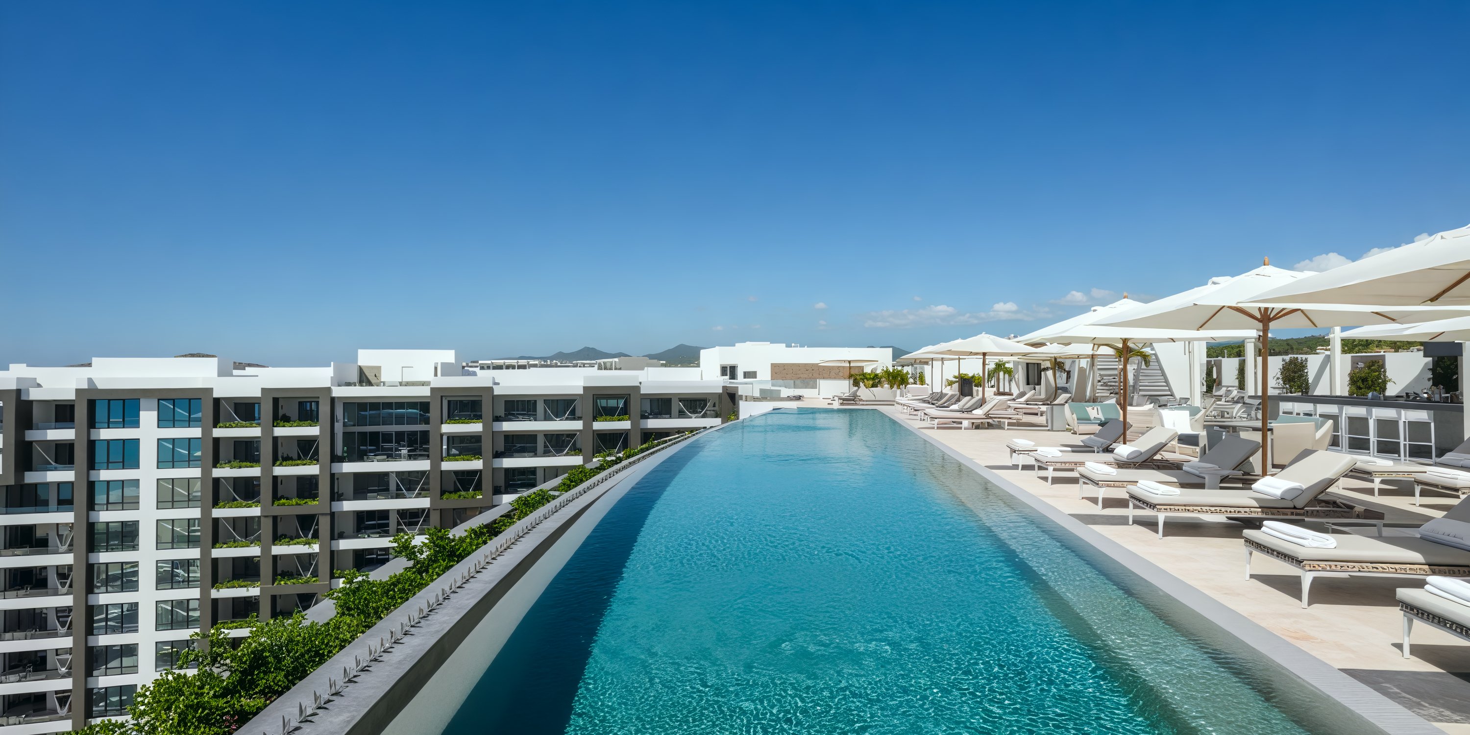 Garza Blanca Los Cabos: Experience the perfect destination wedding setting with a rooftop infinity pool, complete with lounge chairs and breathtaking cityscape views.