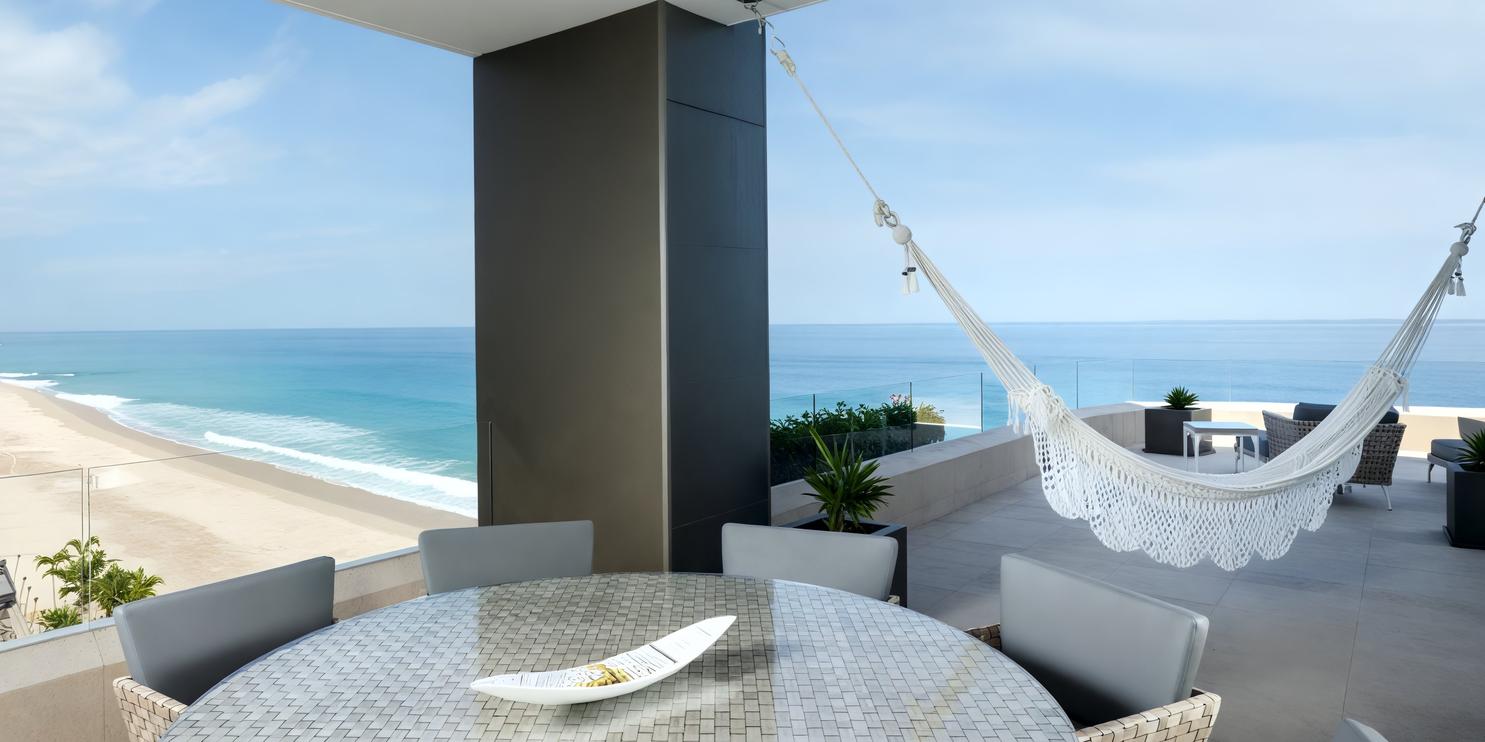 The patio at Garza Blanca Los Cabos, ideal for a destination wedding, features a round table and hammock with breathtaking beachfront views.
