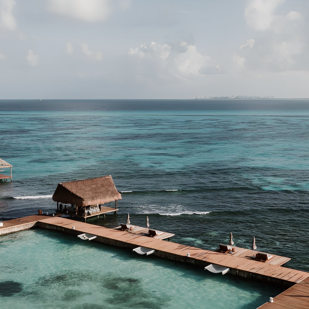Wooden pier and thatched hut over clear turquoise ocean, perfect for a destination wedding setup.