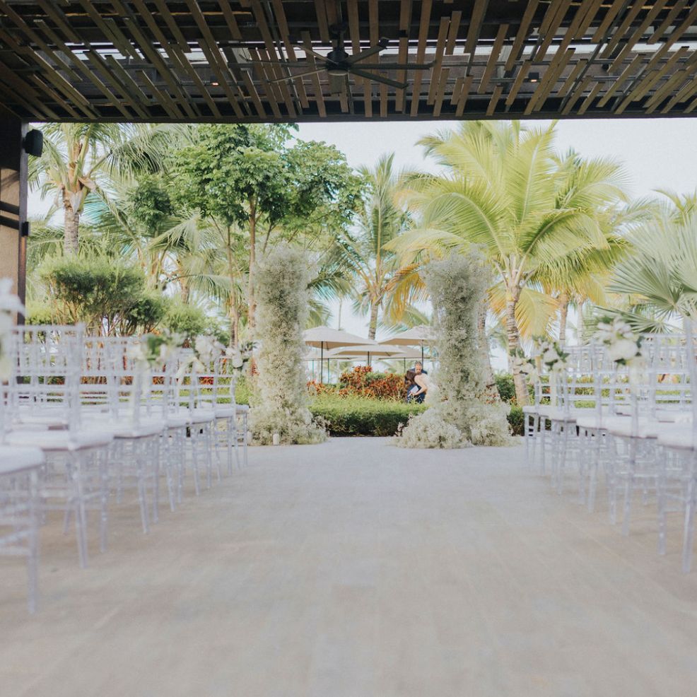A beautiful destination wedding setup with rows of chairs arranged outdoors among lush green trees.