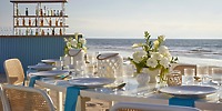 Elegant wedding dining setup on the beach at UNICO 20&deg;105&deg; Riviera Nayarit, with flowers and a bar.