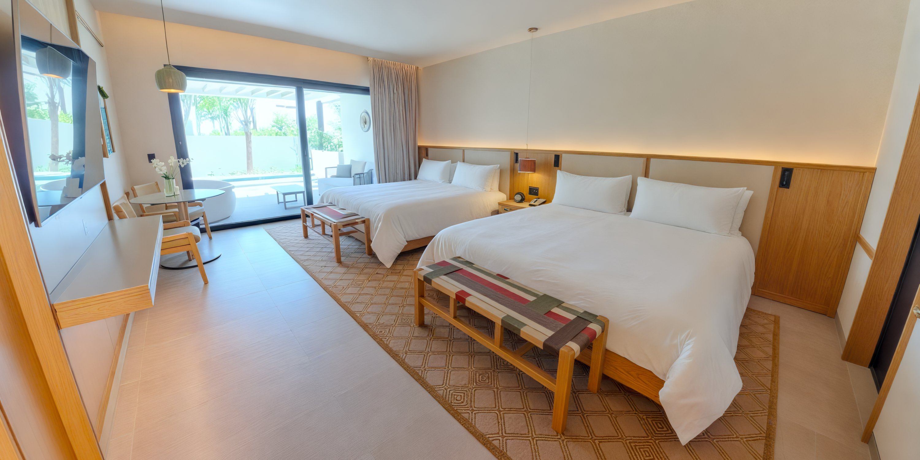 Bright room at UNICO 20°105° Riviera Nayarit perfect for a destination wedding, with 2 large beds, desk, table, and patio access.