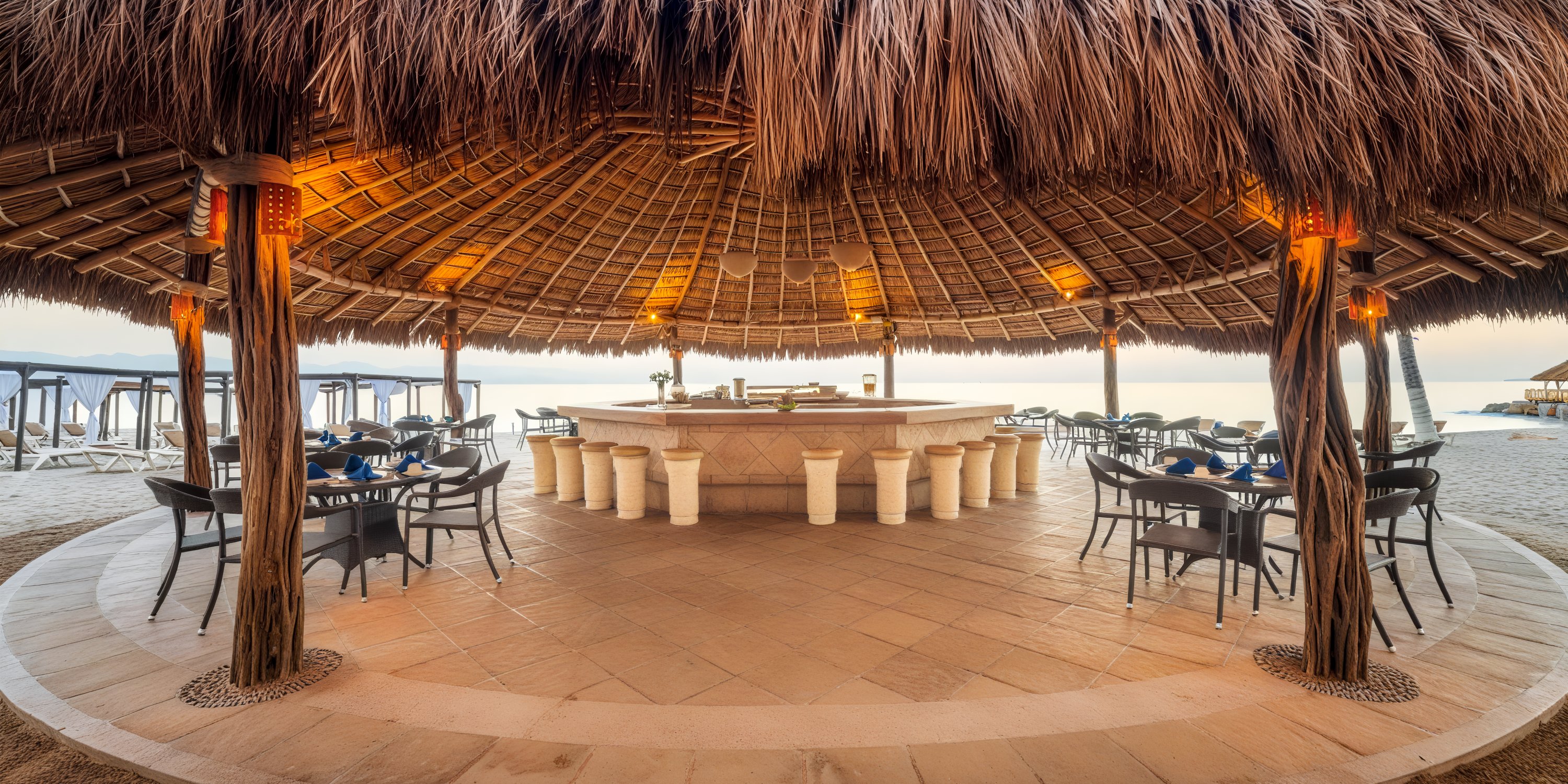 The UNICO 20°87° tiki bar, featuring a charming thatched roof, provides an inviting setting with its surrounding tables set on a tiled floor—an ideal spot for a destination wedding or a memorable wedding reception.