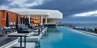 The UNICO 20°87° boasts an infinity pool complete with lounge chairs and ocean views, set against the backdrop of cloudy skies—an ideal setting for a destination wedding.