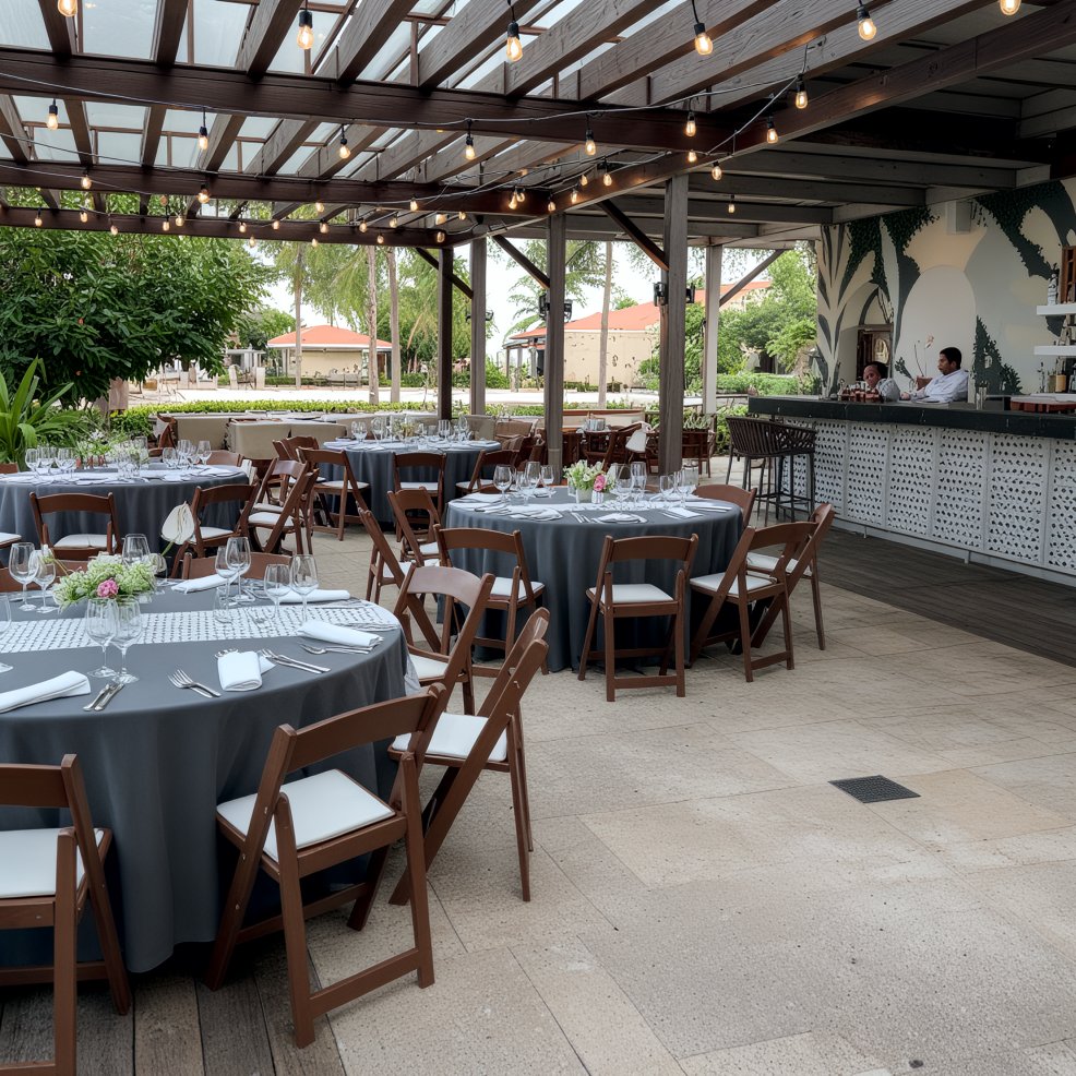 Elegant destination wedding venue featuring round tables with gray linens and a bar on a covered patio.