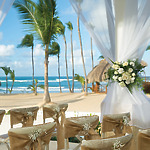 A picturesque beachfront arrangement perfect for a destination wedding, complete with elegantly arranged chairs and beautiful floral decorations.