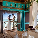 A couple stands together in a wooden gazebo overlooking the ocean—the perfect setting for unforgettable destination wedding photos.