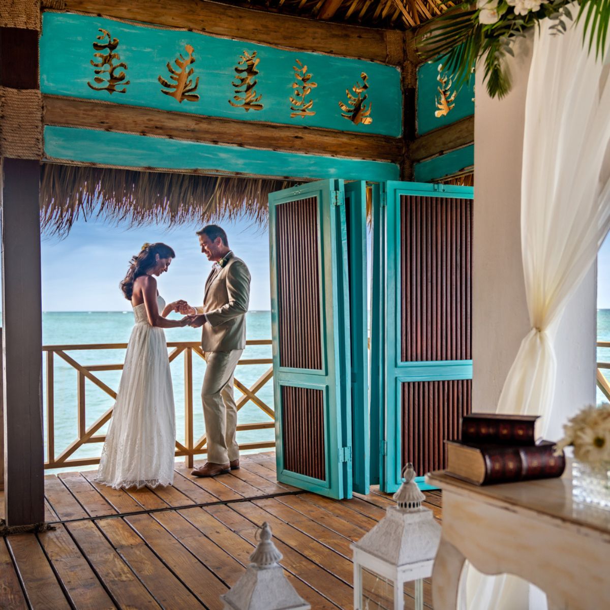 A couple stands together in a wooden gazebo overlooking the ocean—the perfect setting for unforgettable destination wedding photos.