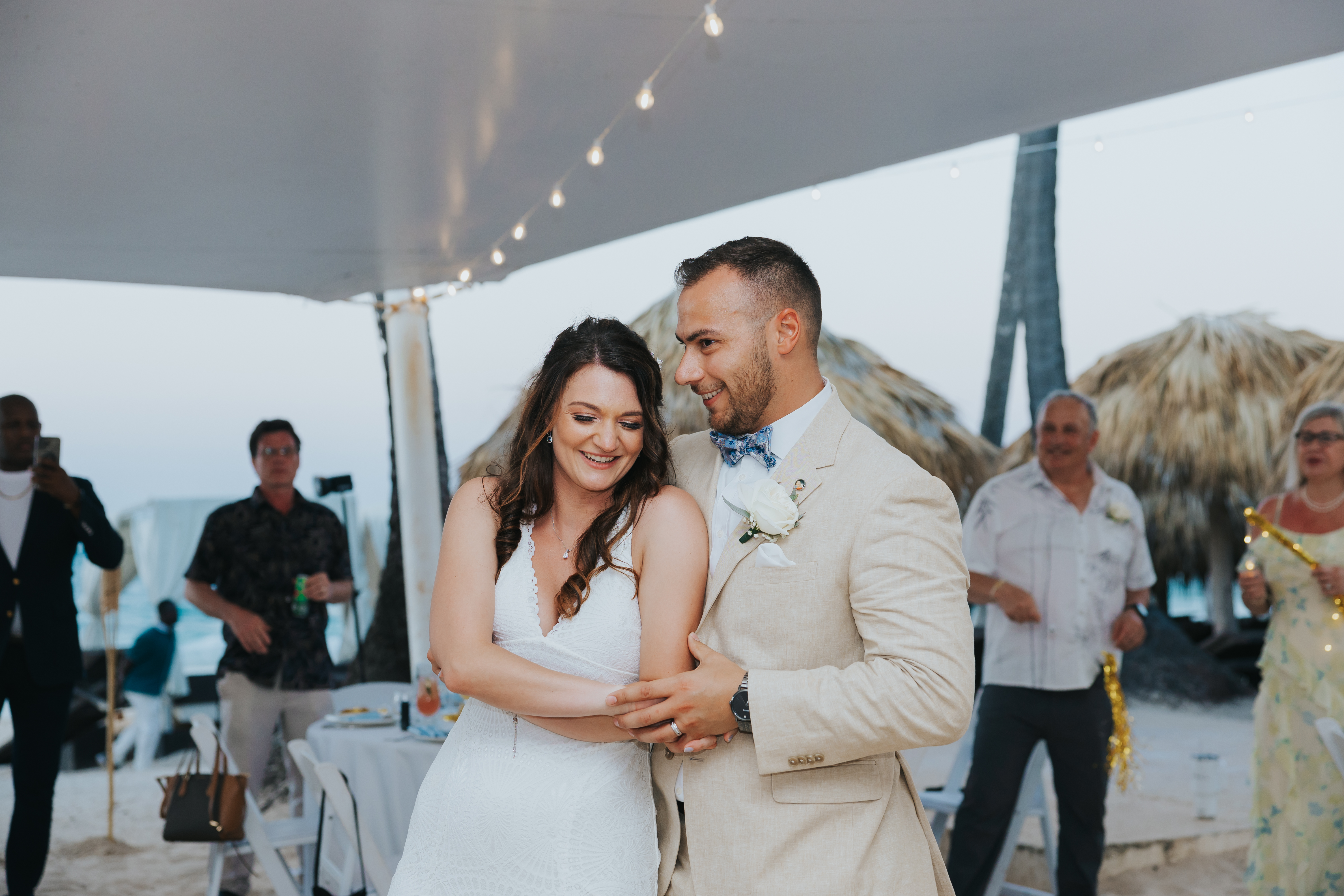 Cathy and Berwick are smiling and dancing together at a joyful outdoor destination wedding reception on the beach.