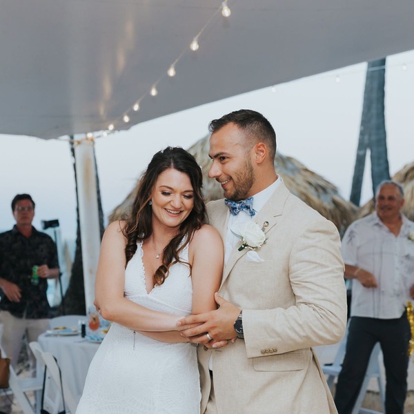 Cathy and Berwick share a joyful smile as they dance together at a beautiful outdoor destination wedding reception.
