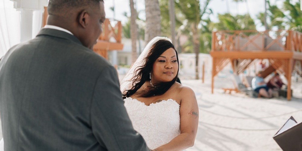 Cathy and Berwick stand side by side outdoors, basking in the sunshine during their beautiful destination wedding ceremony.