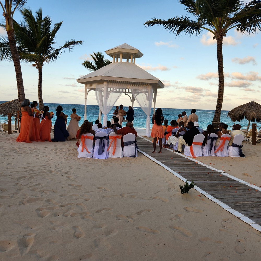 Cheryl and Daryl’s destination wedding features guests seated on beautifully decorated chairs beneath swaying palm trees, with a stunning gazebo as the focal point for their beachside ceremony.
