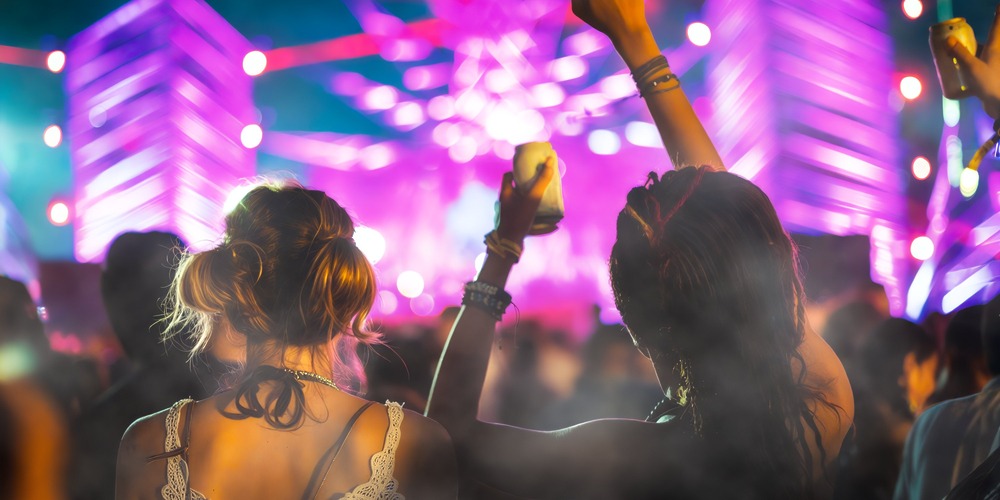 Two people with raised hands revel in the crowd at a destination wedding resort in Jamaica—an ideal spot for music lovers.