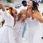 Three women dressed in white celebrate at an outdoor destination wedding at a music lover’s resort in Jamaica.