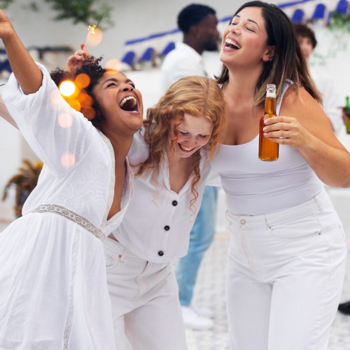Three women dressed in white celebrate at an outdoor destination wedding at a music lover’s resort in Jamaica.
