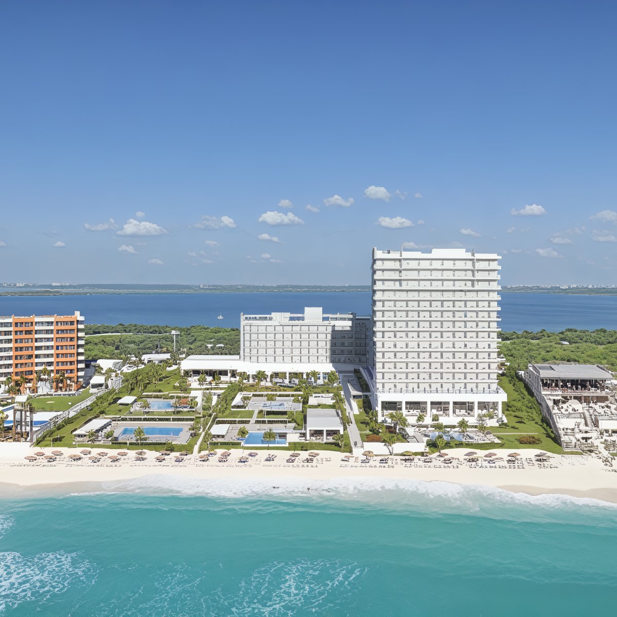 Hotel Riu Ventura: an idyllic beachfront resort, perfect for a destination wedding, featuring beautiful pools and lush gardens, all seen from the ocean beneath clear blue skies.