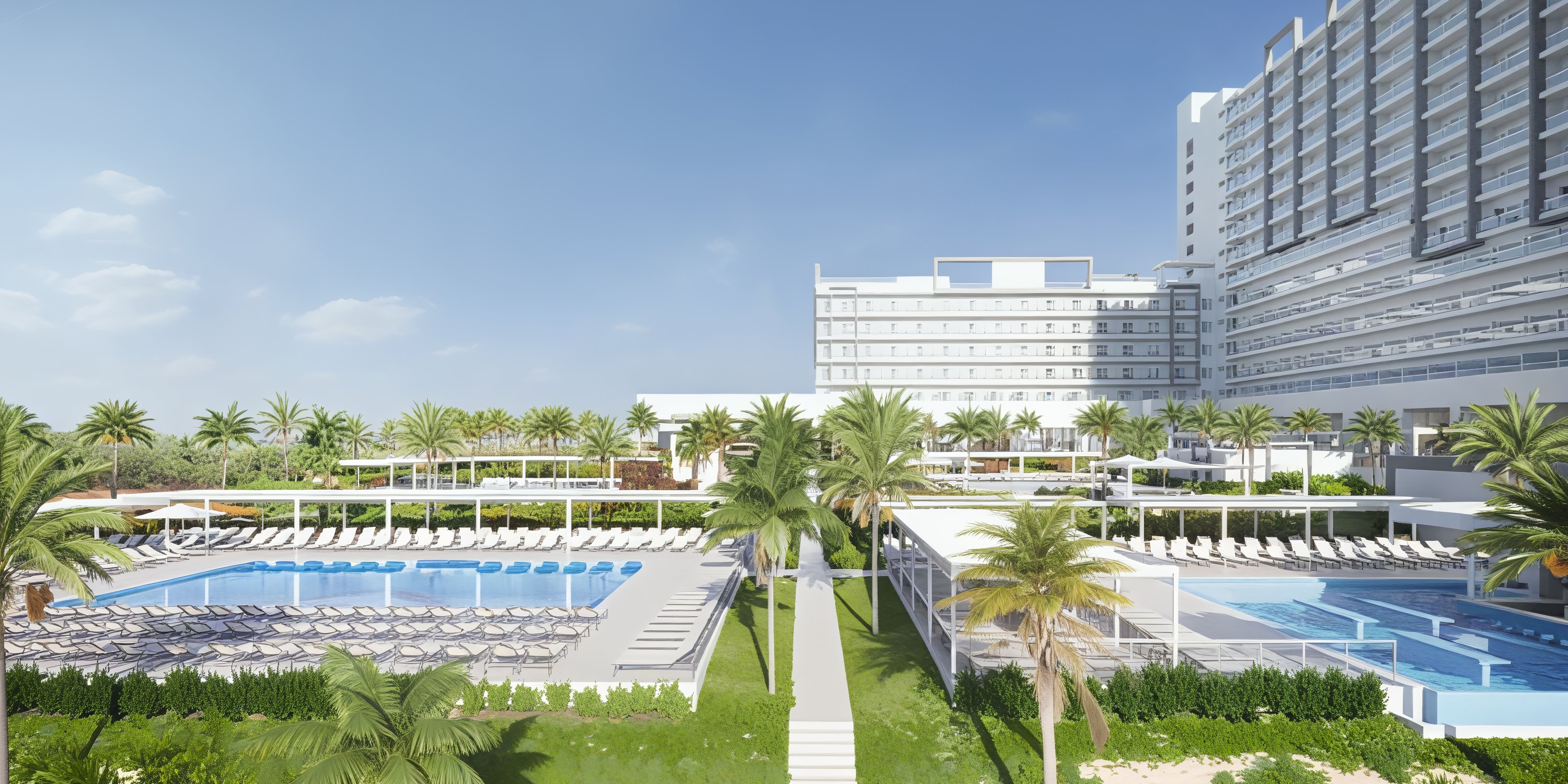 Hotel Riu Ventura: a modern destination wedding resort featuring sparkling pools, elegant lounge chairs, swaying palm trees, and a stunning multi-story hotel—perfect for your dream wedding celebration.