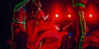 Dancers in vibrant red light up the stage at Hotel Riu Ventura, captivating destination wedding guests under brilliant red lights.