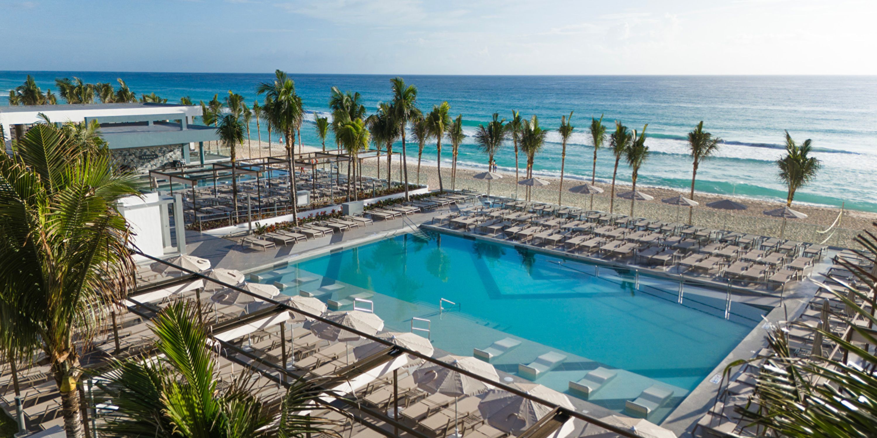 Hotel Riu Ventura: Dreamy poolside with lounge chairs and palms, perfect for a destination wedding.