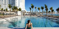 Woman in swimsuit relaxes by Hotel Riu Ventura pool, a popular spot for destination wedding guests.