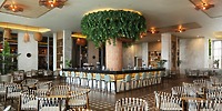 Hotel Riu Ventura, ideal for a destination wedding, boasts a central bar, greenery, and elegant chairs.
