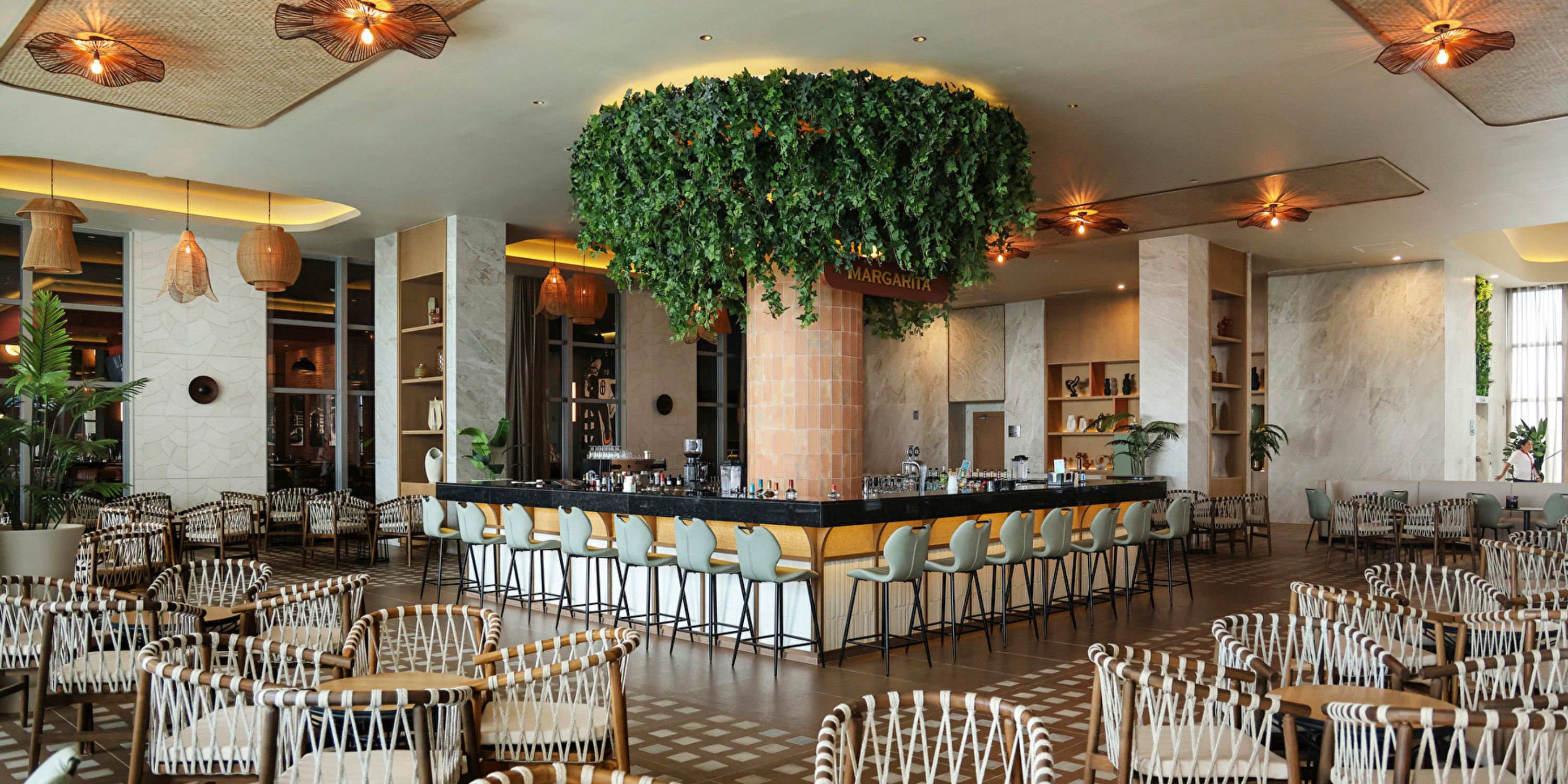 Hotel Riu Ventura, ideal for a destination wedding, boasts a central bar, greenery, and elegant chairs.