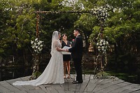 Nancy and David stand with their officiant at an outdoor altar during their destination wedding ceremony.
