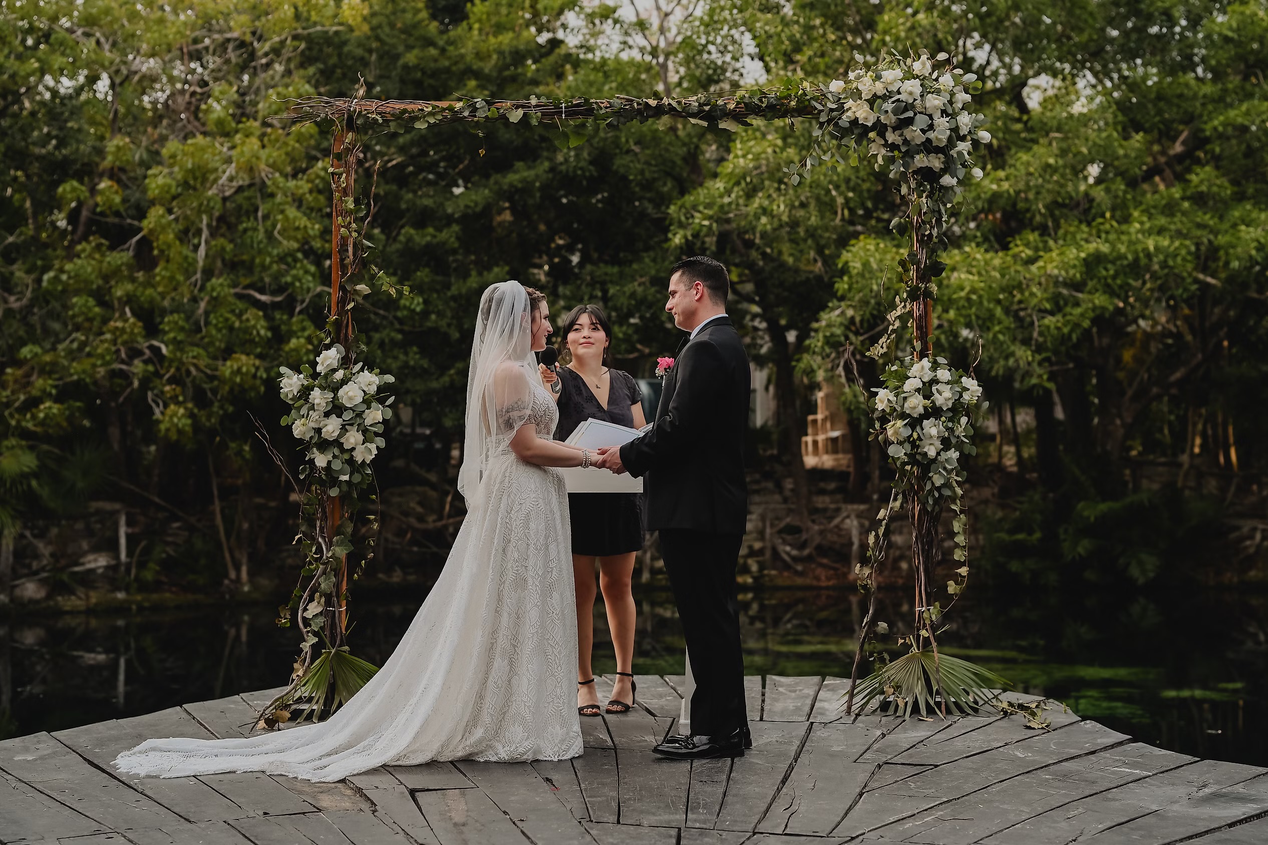 Nancy and David stand with their officiant at an outdoor altar during their destination wedding ceremony.