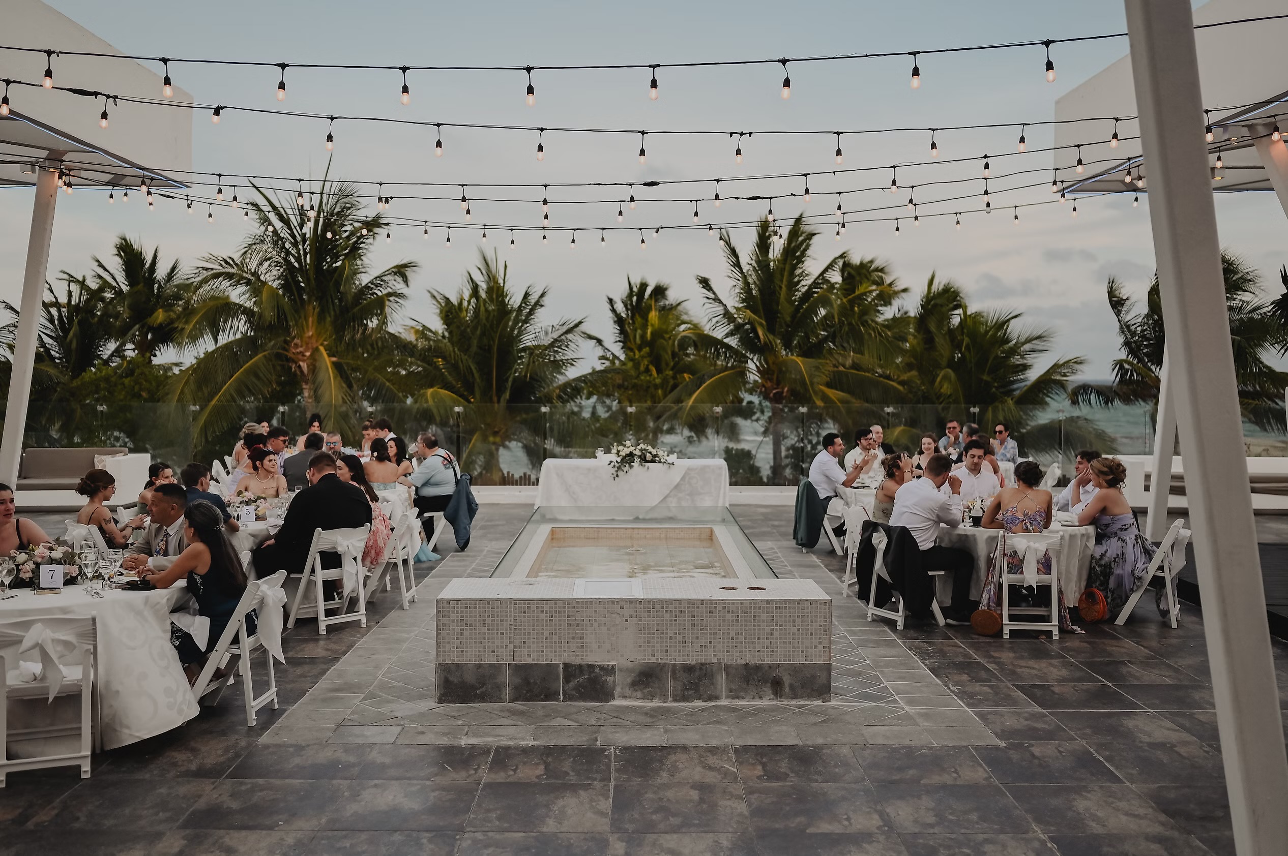 Nancy and David’s destination wedding featured guests seated at round tables beneath twinkling string lights, creating a magical outdoor celebration.
