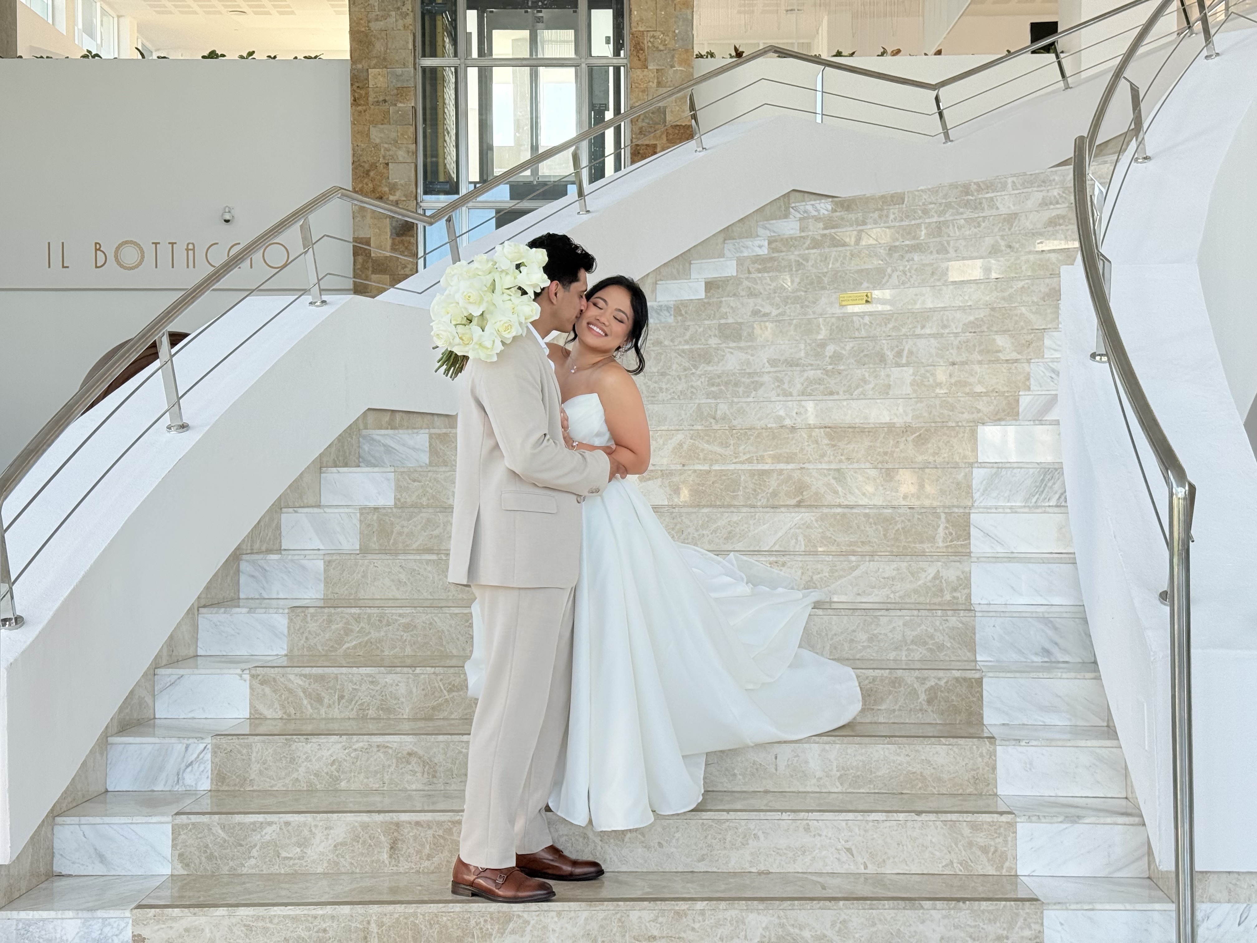 Ashleigh and Dominic share a loving embrace on a marble staircase, dressed in their elegant wedding attire at their beautiful destination wedding.