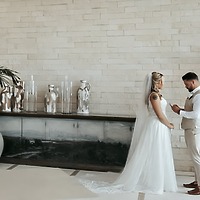 Emily and Stephen stand indoors at their destination wedding, as Stephen reads heartfelt words from a piece of paper.